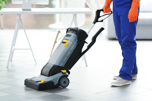 A janitor cleans a floor with a machine.