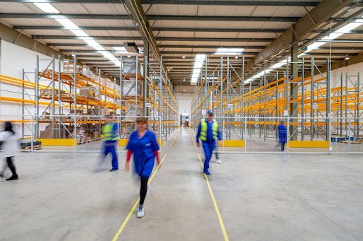 A group of janitorial workers walking inside a warehouse.