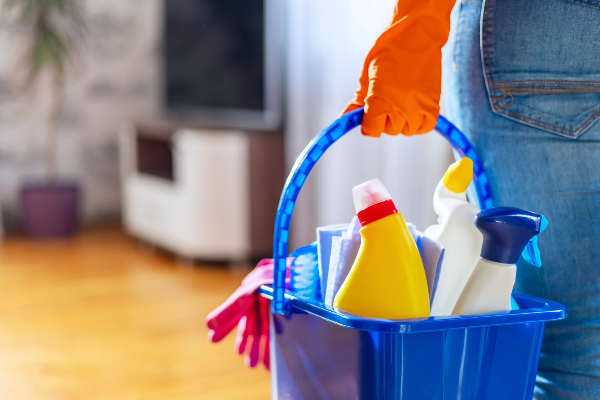 Closeup of a worker in rubber gloves with a bucket of cleaning supplies ready to clean a floor. 